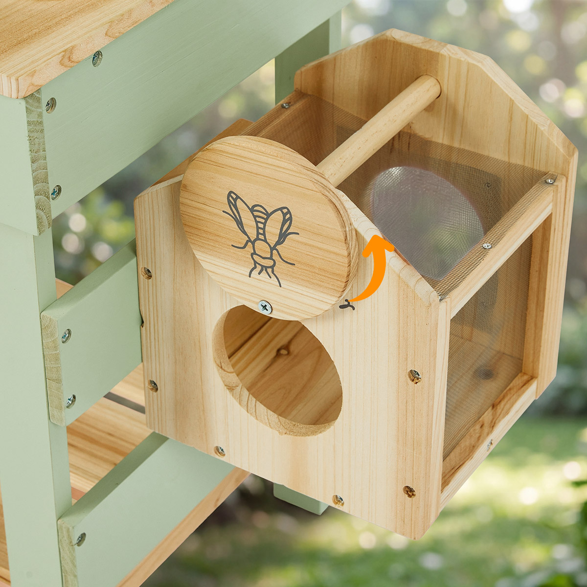 Close-up of wooden bug catcher on green outdoor mud kitchen for kids nature discovery play